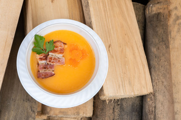 Bowl of pumpkin soup on rustic wooden background. Selective focus