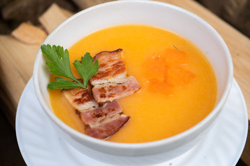 Bowl of pumpkin soup on rustic wooden background. Selective focus