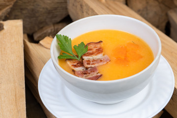 Bowl of pumpkin soup on rustic wooden background. Selective focus