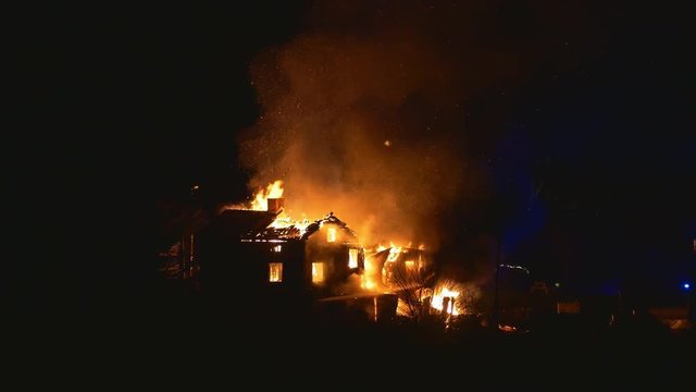 Burning house and fire fighters, parts of the roof collapses during clip