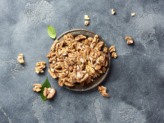 Walnut kernels on plate. Nuts with green leaves. Top view.