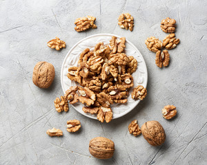 Walnut kernels on white plate over gray background.