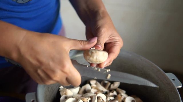 Young woman cutting mushrooms in the kitchen