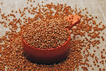 Grains of buckwheat in a clay pot against the background of sackcloth