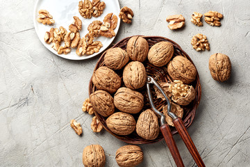 Whole walnuts and kernels on gray background and nutcracker.