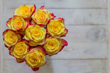Naklejka premium top view of bunch of roses of yellow and red colors with water drops. greeting card concept with copy space