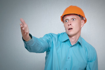 Confused and discouraged builder worker man isolated on gray background.