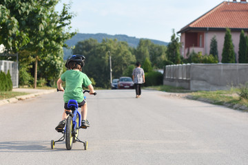 Five years old boy rides a bicycle in the city. Child riding bicycle outdoor on sunny day