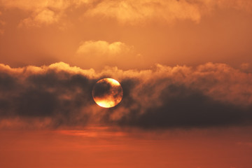 The sun towards the sunset in the clouds spreads orange light