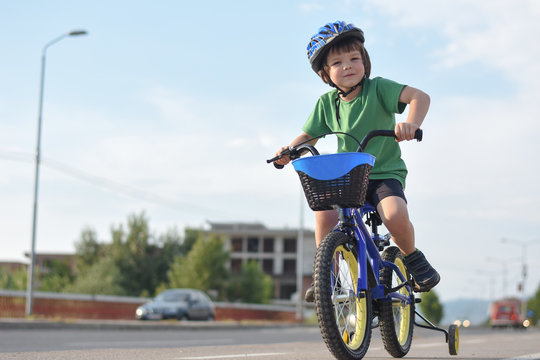 Five years old boy rides a bicycle in the city. Child riding bicycle outdoor on sunny day
