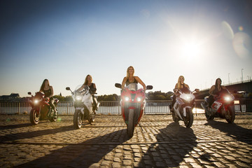 5 Frauen auf Motorrädern am Fluss. Formation. 