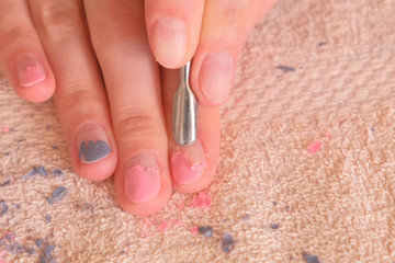 Woman removes shellac from nail with pusher. Close-up hand.