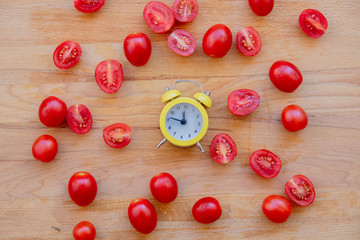 little alarm clock and tomatoes on wooden table. Above view