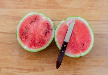 Watermelon and knife on wooden table. Above view