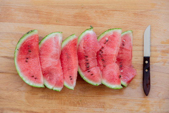Watermelon and knife on wooden table. Above view