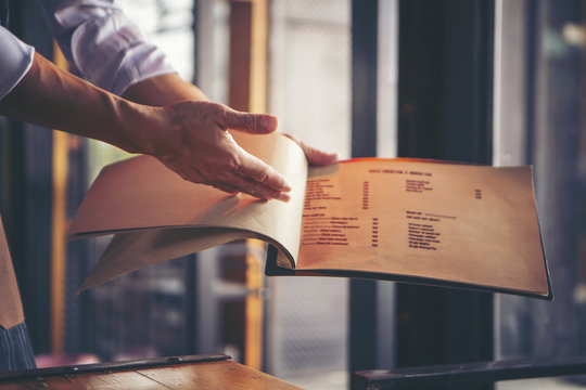 Waiter opening menu to introduce restaurant menu.