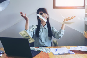 Successful business women are counting money and throwing a dollar at work happily.