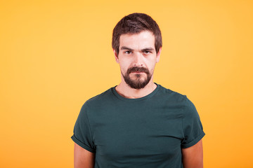 Grumpy stressed worried man on yellow background lookin at the camera. Depression, unhappy and stress concept image