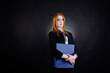 Portrait of a redheaded businesswoman wearing striped blouse, glasses and a jacket with a blue folder.