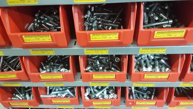 Steel industrial rack of red storage bins with mechanical mounting parts such as nuts, bolts and other hardware CLOSE UP.