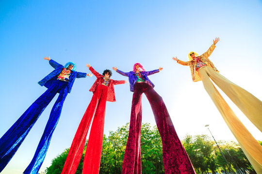 Young people on stilts posing against the blue sky.