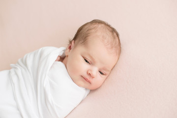 Newborn girl in white wrap on a pink background. Photoshoot for the newborn. 7 days from birth. A portrait of a beautiful, seven day old, newborn baby girl	