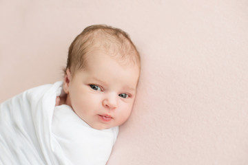 Newborn girl in white wrap on a pink background. Photoshoot for the newborn. 7 days from birth. A...