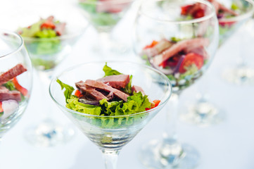 wine glasses with salad and meat snack at reception. catering snack service