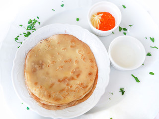 Pancakes with red caviar on white plate