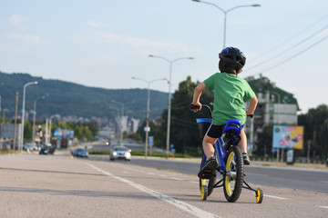 Five years old boy rides a bicycle in the city. Child riding bicycle outdoor on sunny day