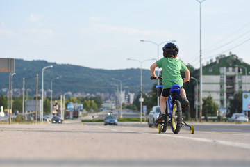Obraz premium Five years old boy rides a bicycle in the city. Child riding bicycle outdoor on sunny day
