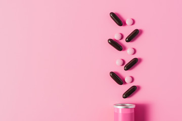 top view of can with arranged pink and black pills on pink