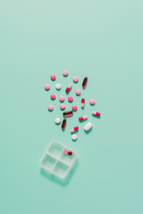 top view of various pills spilled from plastic case on blue