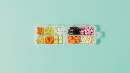 top view of plastic case with various sorted pills on blue