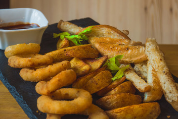 Assorted snacks for beer in the bar. Meat, cheese, onion rings on the grill and deep-fried