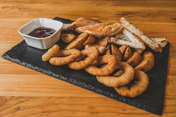 Assorted snacks for beer in the bar. Meat, cheese, onion rings on the grill and deep-fried