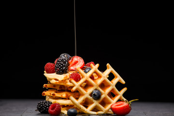 Photo of viennese wafers with berries pouring honey on black empty background