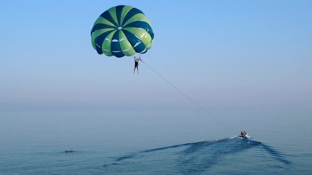 Towing a parachute behind a boat over the sea at sunset. Aerial view.