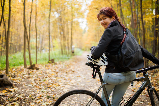 Photo of smiling brunette in jeans next to bicycle