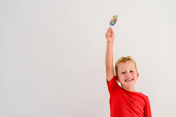 Boy with red shirt on white background eating a lollipop colorful fun and laughing.