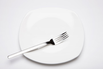 empty white dish with a fork on the white bottom.