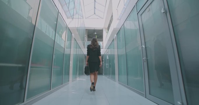 young successful businesswoman walking down office hall with briefcase in hand - business, success concept 4k