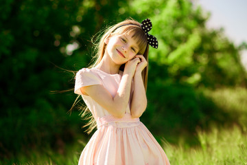 Portrait of beautiful little girl in elegant dress in middle of green summer field