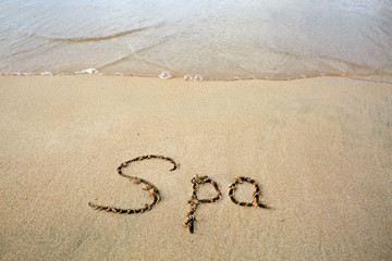 Word Spa written on the sand near the sea.Vacation concept.