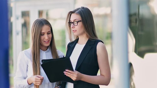 Two female businesswoman having informal team meeting standing outdoor near office