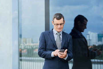 Middle-aged businessman checking messages in his smartphone