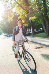 asian student in eyeglasses with backpack riding bicycle on street