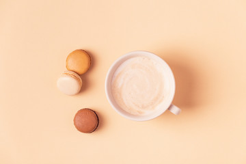 Cup of coffee with macaroons on pastel background.
