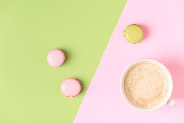 Cup of coffee with macaroons on pastel background.