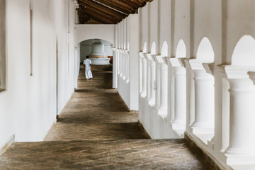 Man dressed in white walking in a corridor of a buddhist temple